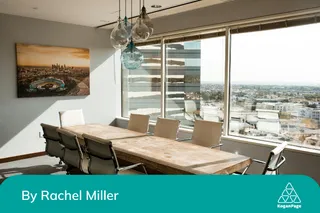 Picture of an empty meeting room with a long table and chairs next to a big window at a high-rise building