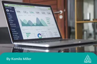 A laptop open on a desk displaying Google Analytics dashboard with various graphs and metrics visible on the screen.