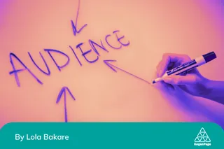 The word audience written on a board, a hand holding a marker having finished writing, and three arrows pointing to the word audience to indicate it's important in marketing with cultural literacy.