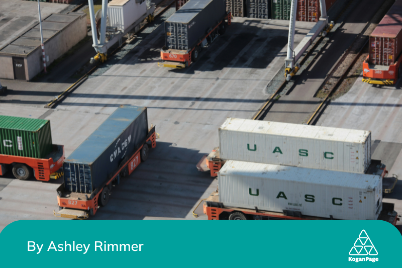 Aerial view of a busy shipping container yard with multiple trucks moving and stationary containers.