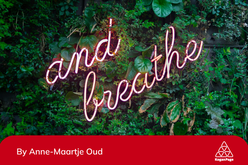 A plant wall with the words 'and breathe' in neon