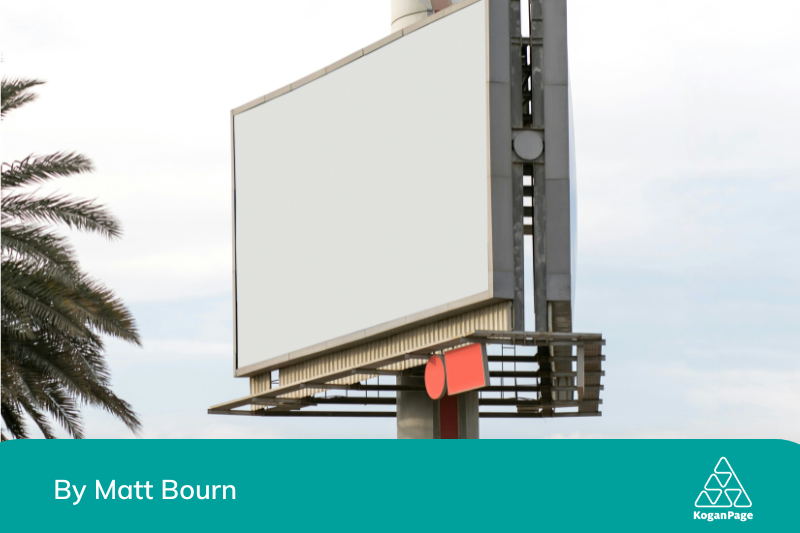 A visual display screen outdoors, with a slight view of a palm tree fronds. The visual display is blank.