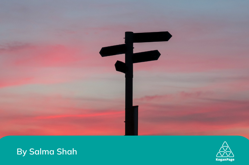 Signposts pointing in different directions in front of a pink sunset 