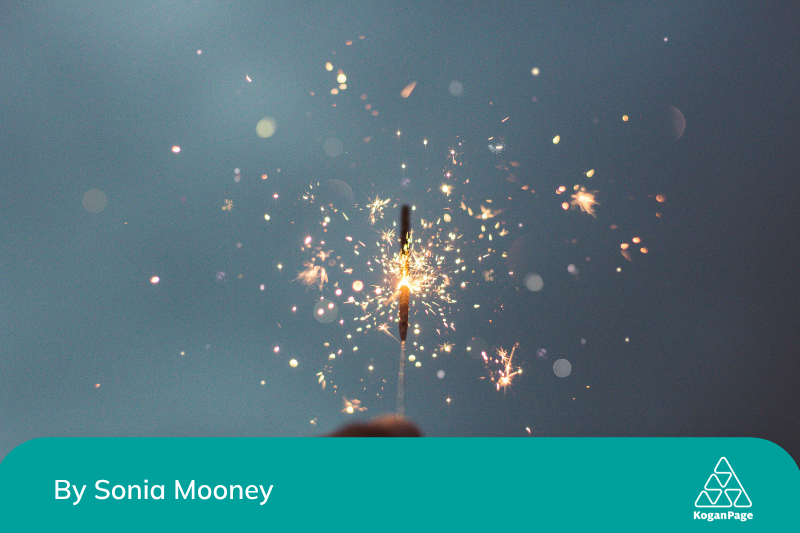 Person holding sparklers with a blurred background.