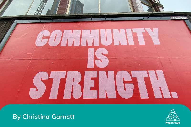A red billboard with pink and white lettering saying ‘community is strength'.